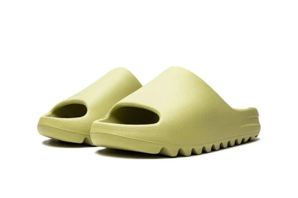 "Adidas Yeezy Slide 'Resin' in light green, one-piece slip-on design with soft footbed, midfoot arch support, and grooved outsole for durability and traction."